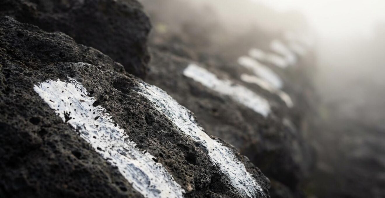 Gros plan sur les marques blanches peintes sur la lave noire avec brume atmosphérique